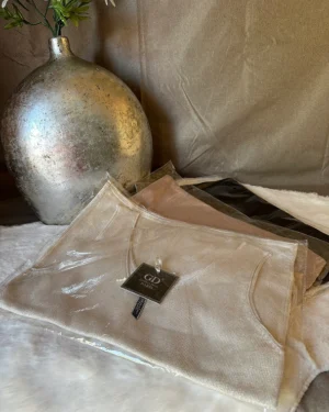 Mouwloze V-hals top van Golden Days. Verkrijgbaar in beige, taupe en zwart. Comfortabel, stijlvol en perfect voor elke outfit.