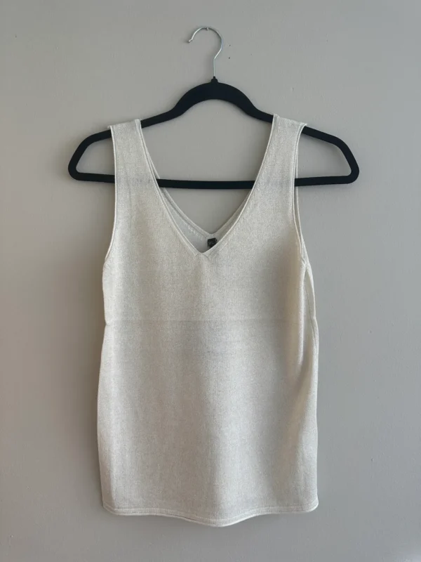 Elegante mouwloze top in lichtbeige met diepe V-hals, gemaakt van een zachte, luchtige stof.