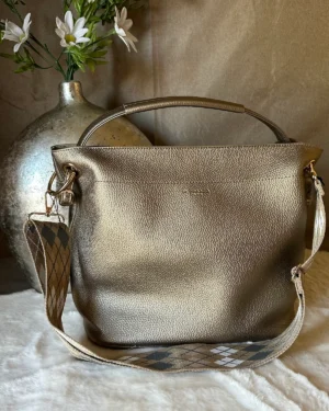 met een luxe bronskleurige finish, stevige handgreep en afneembare schouderband met grafisch patroon. Verkrijgbaar in meerdere kleuren