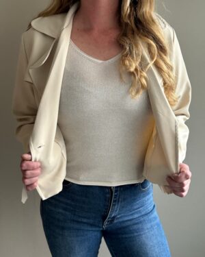 Elegante mouwloze top in lichtbeige met diepe V-hals, gemaakt van een zachte, luchtige stof.